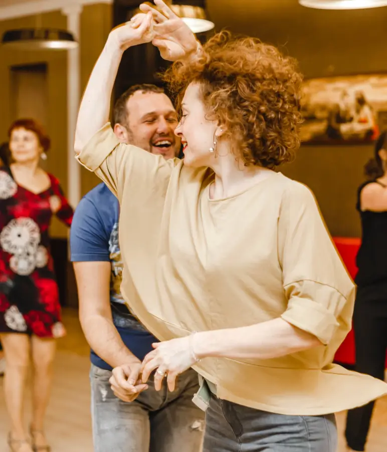 Tanzcoach bespricht mit einem Paar entspannt die Choreografie am Rand des Saals